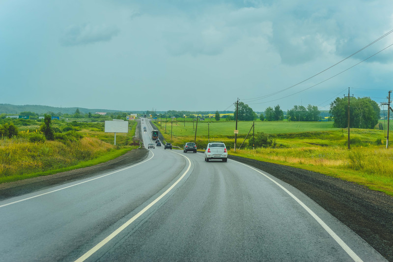 在时而阴天时而下雨的俄罗斯公路上行驶, 两旁是平坦的东欧平原 公路